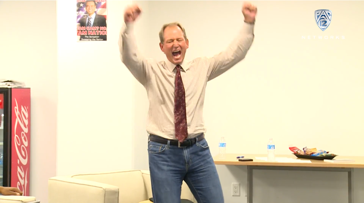 Rick Neuheisel with arms raised watching his son Jerry lead UCLA to victory, 2014